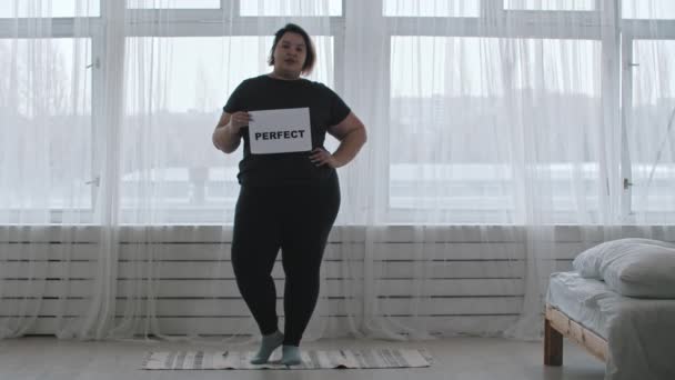 Concetto di positività del corpo - una donna paffuta tiene un segno con l'iscrizione PERFETTO - Filmati, video