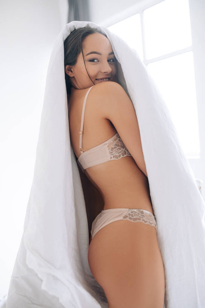 Mulher sexy atraente em lingerie rendas tem uma diversão, envolve em cobertor e sorrisos. - Foto, Imagem
