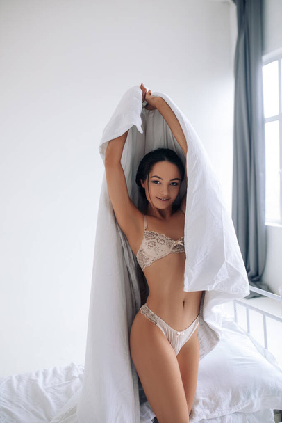 Mulher sexy atraente em lingerie rendas tem uma diversão, envolve em cobertor e sorrisos. - Foto, Imagem