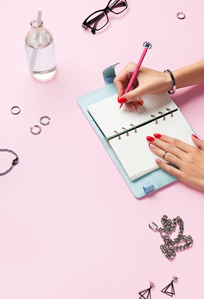 Δημιουργική σύνθεση με γυναικεία χέρια, σχεδιαστής τέλος αξεσουάρ πάνω από ροζ τραπέζι - Φωτογραφία, εικόνα