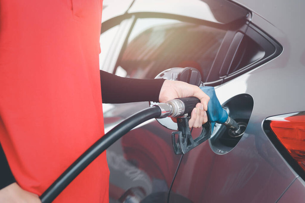 Pracownik stacji benzynowej trzymający dyszę pompy paliwa przed zatankowaniem samochodu benzyną na stacji benzynowej. - Zdjęcie, obraz