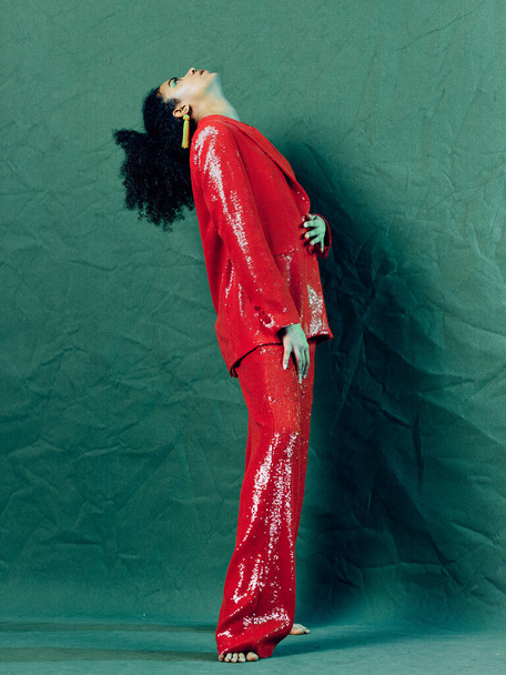 žena s kudrnaté vlasy červená oblek luxusní zelené pozadí model - Fotografie, Obrázek