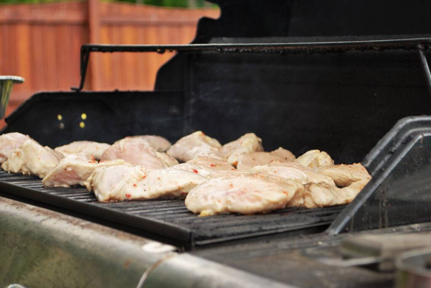 Cuisson de poulet cru sur le gril pour un barbecue dans la cour - Photo, image