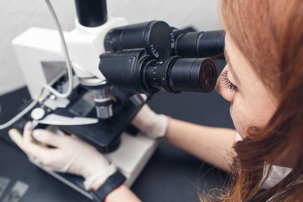 女性研究室の助手が化学実験室の顕微鏡で調べ. - 写真・画像
