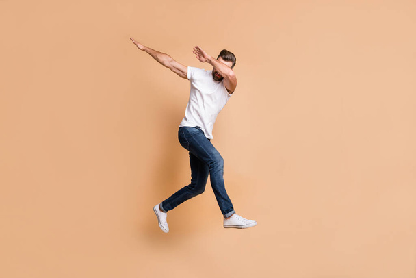 Full length body size view of nice tall fit funky guy jumping having fun dab move isolated over beige color background - Фото, зображення