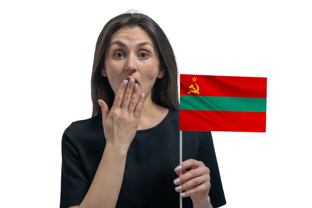 Happy young white woman holding flag of Transnistria and covers her mouth with her hand isolated on a white background. - Photo, Image