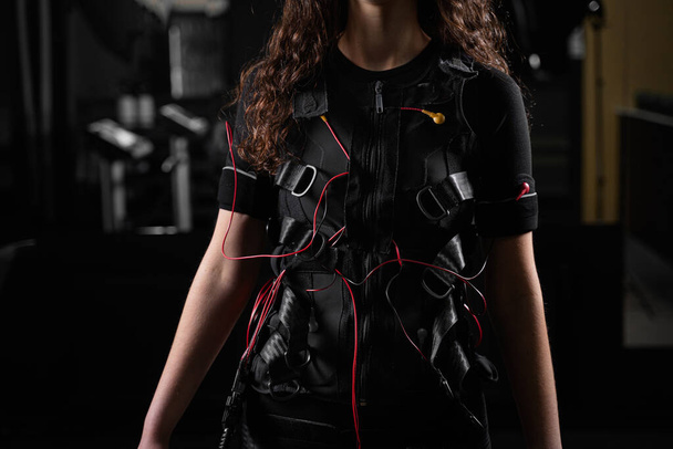 Girl in EMS suit in gym. Sport training in electrical muscle stimulation suit - Фото, изображение