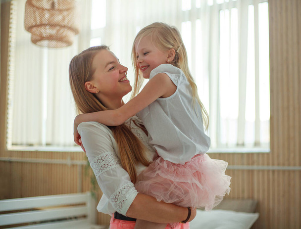 Mother and daughter having fun playing at home in the room together - Foto, Imagen