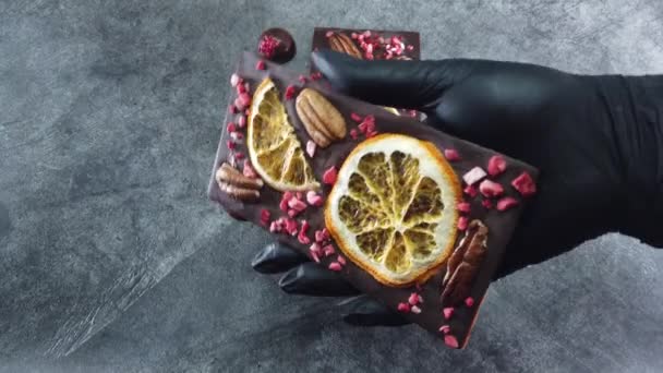 Barra de chocolate hecha a mano se muestra sosteniendo en sus manos. Chocolate hecho a mano de lujo con especias, bayas secas y nueces. - Imágenes, Vídeo