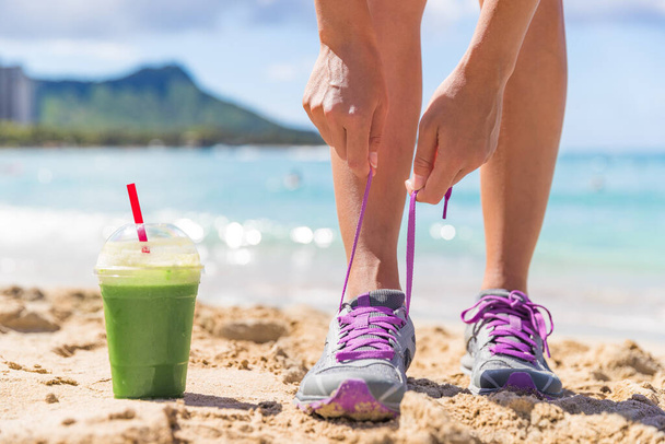 Groene smoothie fitness vrouw strikken loopschoenen - Foto, afbeelding