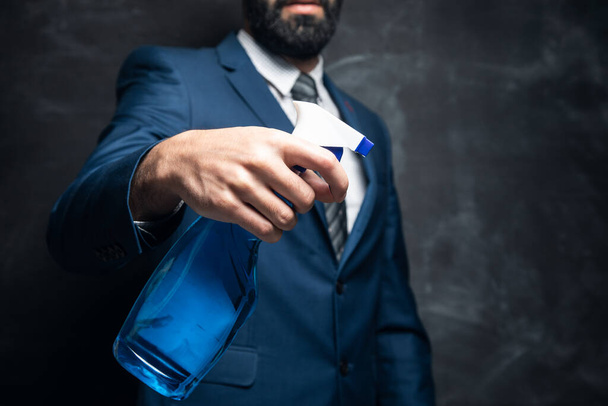 businessman holding detergent on dark background - Foto, Bild