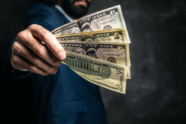 businessman gives money on gray background - Foto, afbeelding