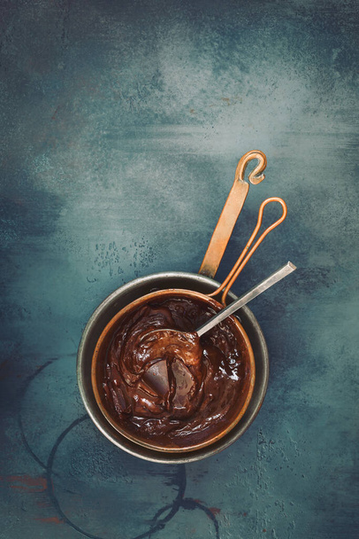 Melted chocolate in a copper pan on rustic surface. Top view, blank space - Foto, Imagem