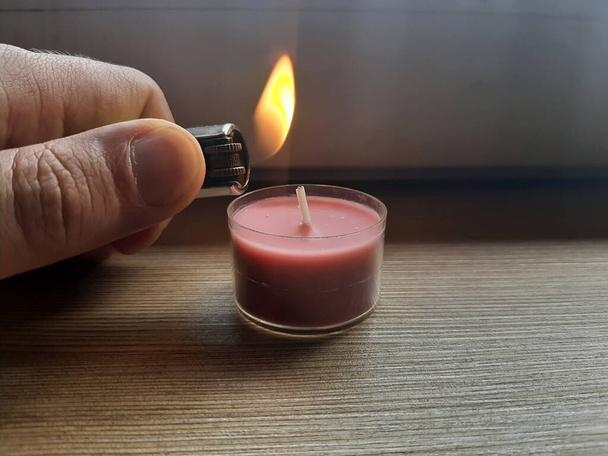 Lighting candle with a lighter. Hand holding lighter with flame. - Photo, Image