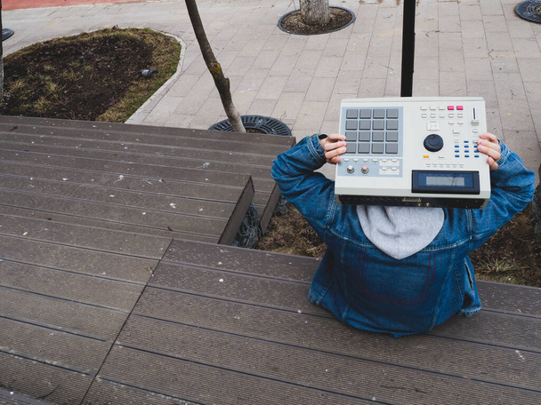 Egy hip-hop beatmaker a parkban egy 90-es évekbeli dobgépet tart a kezében. Retro digitális hangszer hip-hop gyártók és Beatmakers számára - Fotó, kép