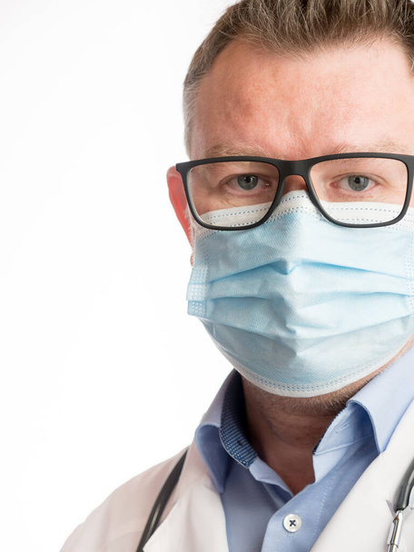 Portrait of a medical doctor wearing a facemask, on white background - Photo, image
