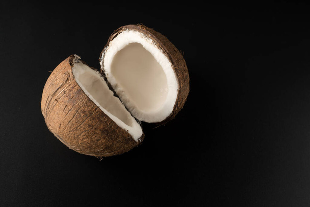 Jeden zralý kokos rozdělený na dvě části, na černém pozadí - Fotografie, Obrázek