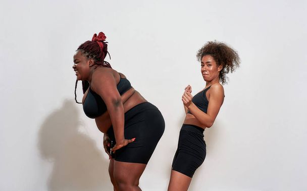 Two afro women with S and XXl size standing over the wall - Fotó, kép