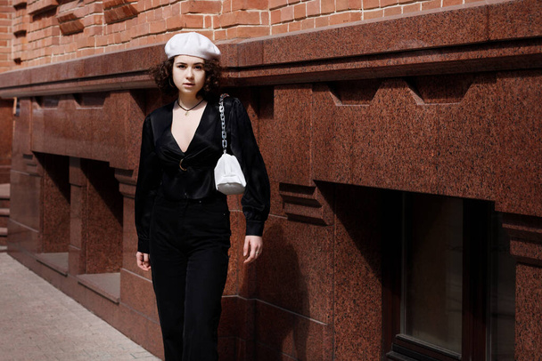 Lány fehér sapkában közel barna épület egy séta a városban - Fotó, kép