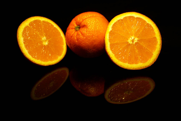 Two  half and an orange isolated on black with reflections - Photo, Image
