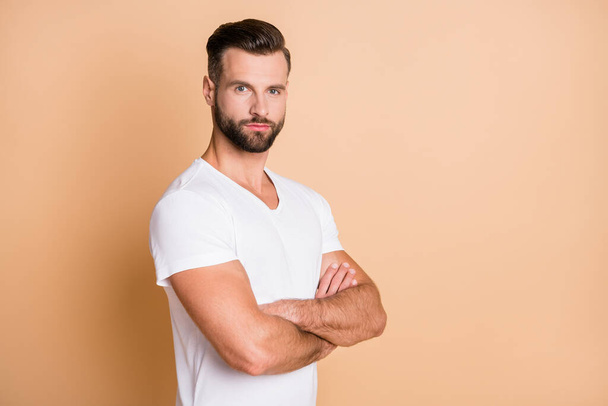 Profile side view portrait of nice attractive virile brunet guy folded arms copy space isolated over beige pastel color background - Fotó, kép
