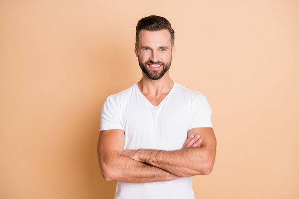 Photo of young handsome man happy positive smile confident crossed hands isolated over beige color background - Valokuva, kuva