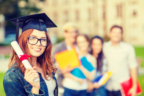 smiling teenage girl in corner-cap with diploma - Foto, imagen