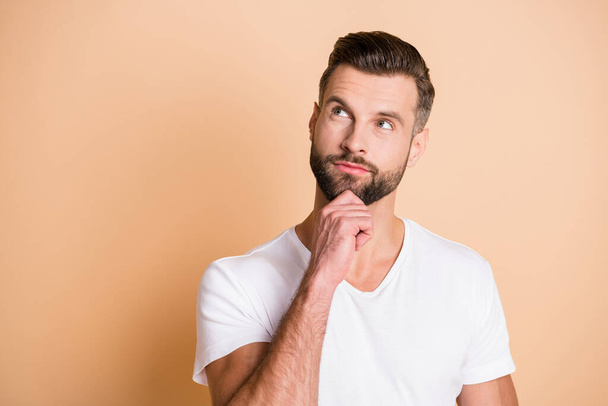 Photo of young handsome man dream dreamy curious look empty space hand touch chin isolated over beige color background - Foto, imagen