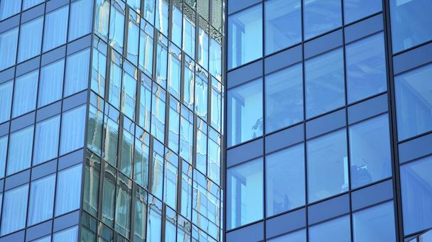 Die verglaste Fassade eines Bürogebäudes mit reflektiertem Himmel. Moderne Architektur Gebäude Außenkulisse. Wolkenhimmel-Reflexion. - Foto, Bild