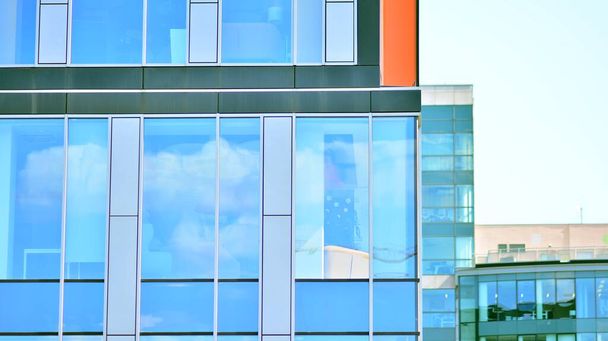 La fachada acristalada de un edificio de oficinas con cielo reflejado. Edificios de arquitectura moderna fondo exterior. Nubes reflejo del cielo. - Foto, imagen