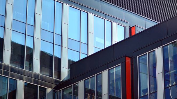 Η γυάλινη πρόσοψη ενός κτιρίου γραφείων με ανακλώμενο ουρανό. Σύγχρονη αρχιτεκτονική κτίρια εξωτερικό φόντο. Σύννεφα αντανάκλαση του ουρανού. - Φωτογραφία, εικόνα