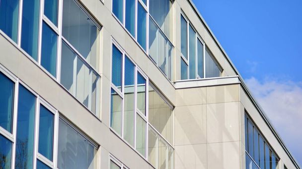 Ein Fragment moderner Architektur, Wände und Glas. Fenster und Balkone eines Wohnhauses vor blauem Himmel. Detail des neuen Luxus-Hauses und Wohnkomplex. Ein Teil der städtischen Immobilien und Eigentumswohnungen Architektur.   - Foto, Bild