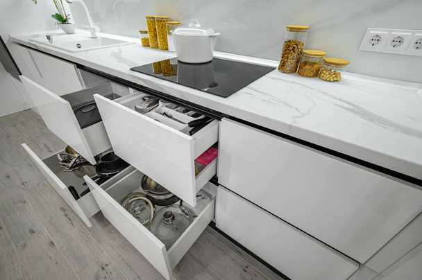 Luxurious white and black modern kitchen interior, drawers pulled out - Photo, Image