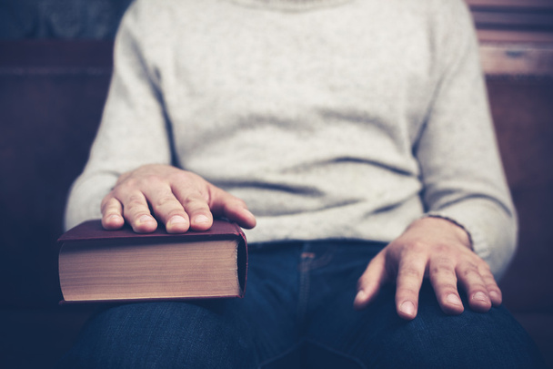 ο άνθρωπος που κάθεται με το χέρι σε ένα βιβλίο - Φωτογραφία, εικόνα