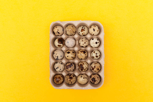 Quail eggs in package on yellow background. Top view, copy space. - Photo, image