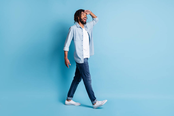 Full length body size profile side view of nice cheerful guy walking looking far isolated over bright blue color background - Photo, image