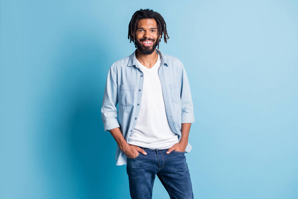 Photo of satisfied dark skin person put hands in pockets smile look camera isolated on blue color background - Valokuva, kuva