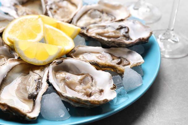 Fresh oysters with lemon on grey table, closeup - Fotoğraf, Görsel