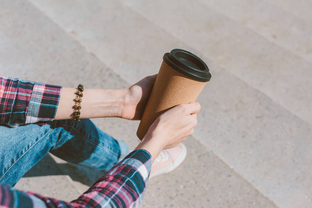 The girl holds a thermo mug with coffee in her hand - Фото, зображення