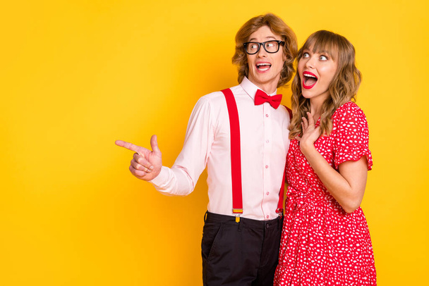Photo portrait of lovely couple smiling impressed surprised man pointing finger on empty space isolated vivid yellow color background - Foto, immagini