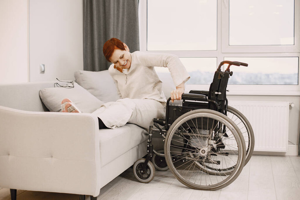 Senior woman trying to sit down in wheelchair from couch - Φωτογραφία, εικόνα