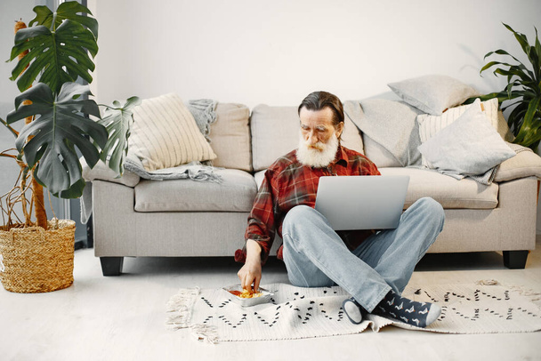 Senior man working with laptop in living room - Photo, image