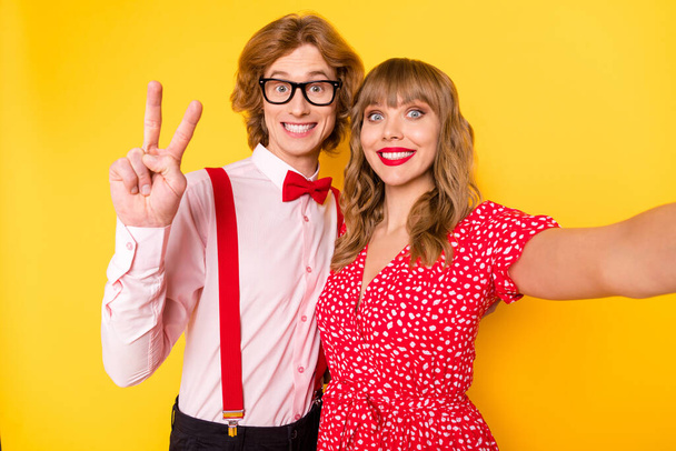 Photo portrait of lovely couple taking selfie guy showing v-sign peace smiling isolated on bright yellow background - Fotografie, Obrázek