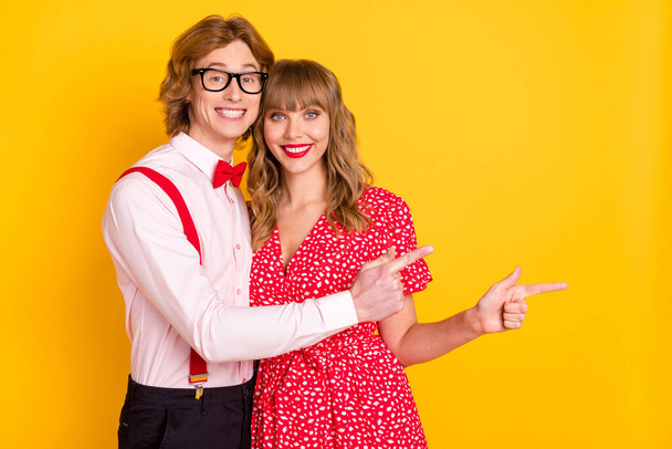 Photo portrait of lovely couple showing finger on blank space advertising isolated on bright yellow background - Foto, Imagen