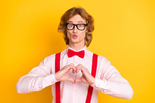 Photo portrait of geek with red hair sending air kiss showing heart symbol fingers isolated on vivid yellow background - Foto, Imagen