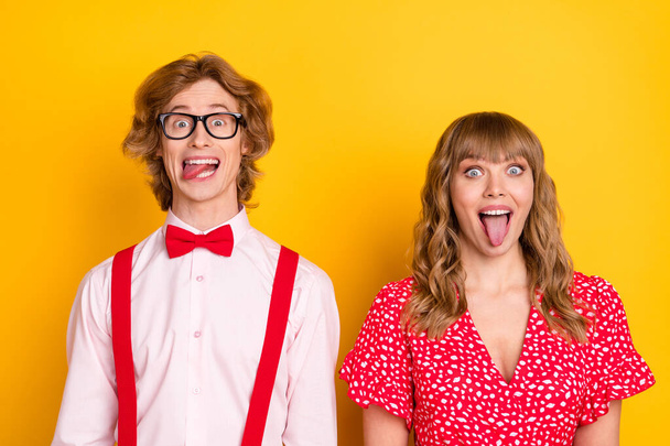Photo portrait of couple fooling grimacing funny showing tongue isolated on vivid yellow background - Zdjęcie, obraz