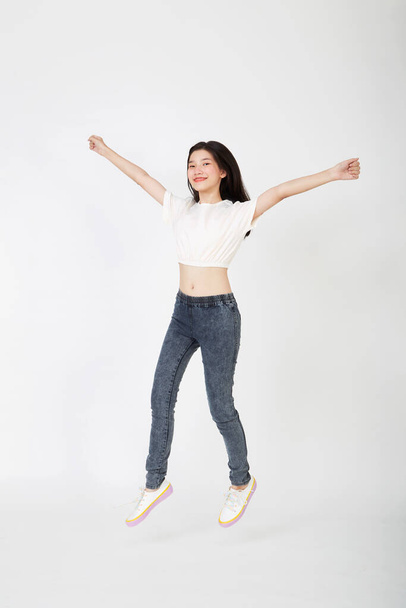 Back to school.Young beautiful Asian woman student jumping on white background - Zdjęcie, obraz