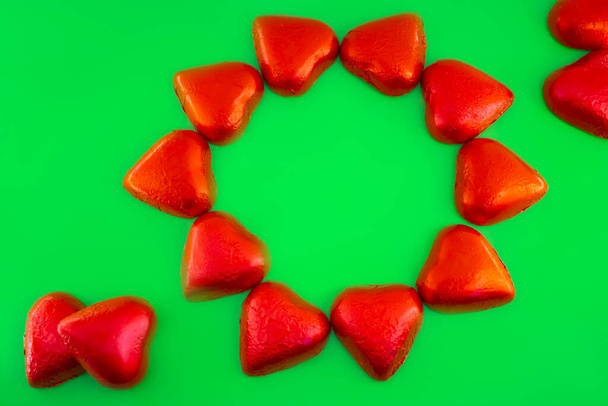 Chocolate candies shape of hearts on green background - Фото, зображення