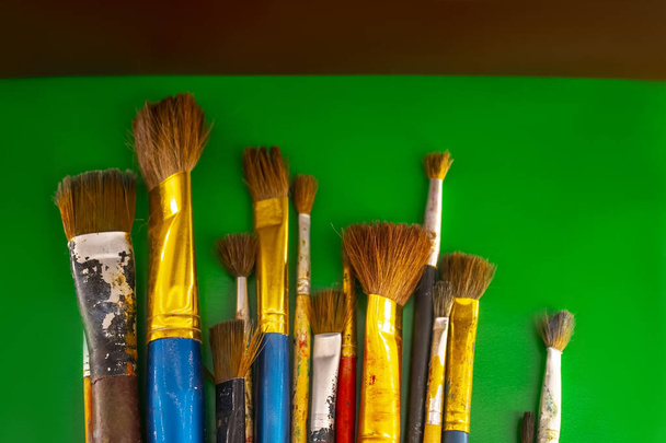 oude penselen voor verf op een groene achtergrond - Foto, afbeelding