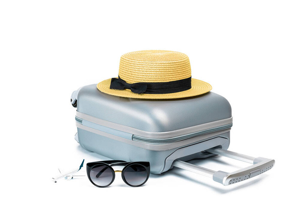 Travel suitcase isolated. Travel accessories with suitcase, straw hat, toy airplane in minimal trip vacation concept isolated on white background. Design of summer vacation holiday concept - Photo, image